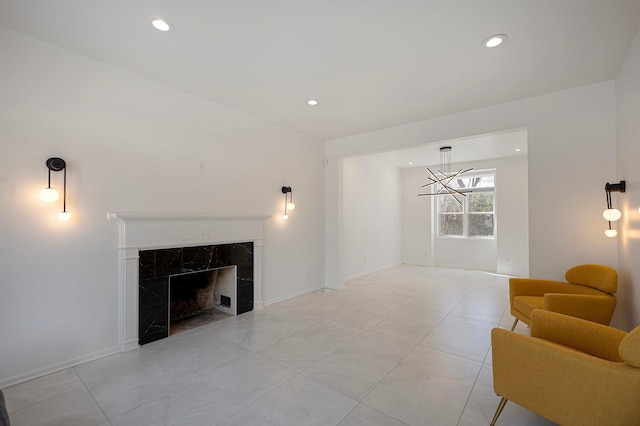 living area featuring a high end fireplace, baseboards, an inviting chandelier, and recessed lighting