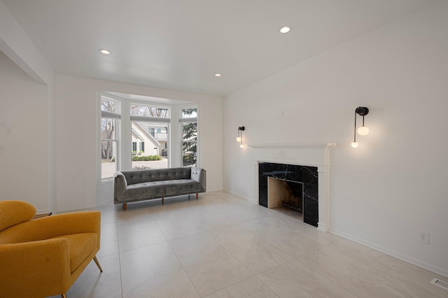 living area with baseboards, recessed lighting, and a premium fireplace