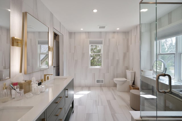 bathroom with tile walls, visible vents, a healthy amount of sunlight, and a sink