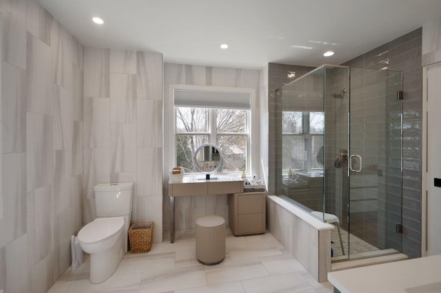 bathroom featuring tile patterned flooring, a shower stall, toilet, and tile walls