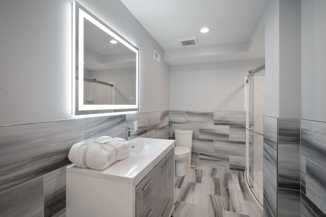bathroom with vanity, tile walls, visible vents, and a stall shower
