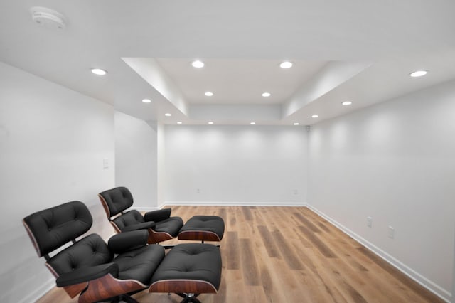 sitting room featuring light wood-style floors, baseboards, a tray ceiling, and recessed lighting
