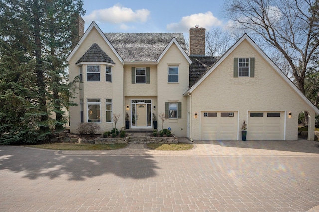 view of front of property with a garage, decorative driveway, and a chimney