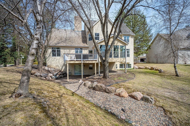 rear view of property featuring a yard, a deck, and stucco siding