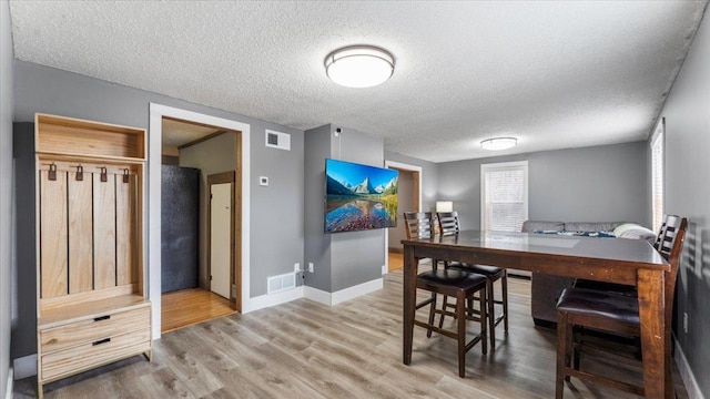 dining area with a textured ceiling, wood finished floors, and baseboards