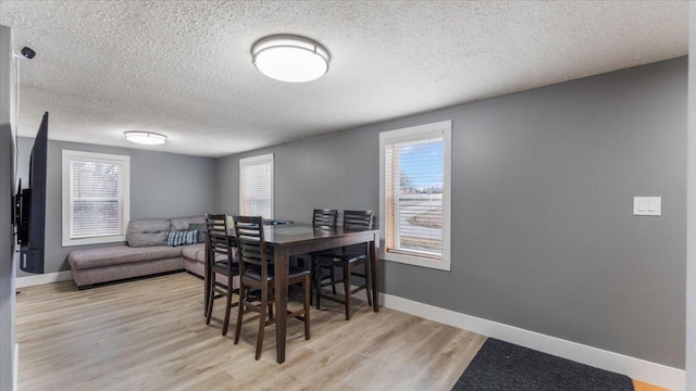 dining area featuring wood finished floors, a textured ceiling, and baseboards