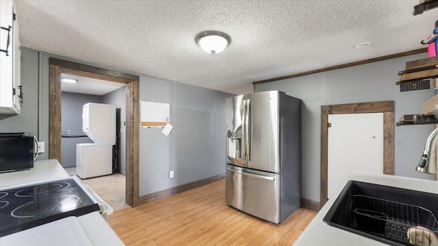 kitchen with stainless steel refrigerator with ice dispenser, black microwave, a sink, light wood-style floors, and electric stove