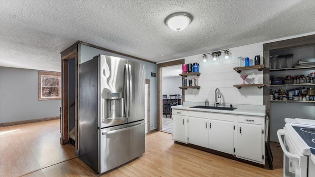 kitchen with stainless steel refrigerator with ice dispenser, a sink, white range with electric stovetop, open shelves, and a textured ceiling
