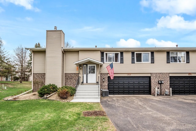 3903 Gershwin Ave N, Oakdale, MN 55128 - bi-level home featuring brick siding, a front yard, driveway, and a chimney