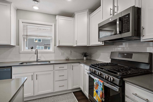 2166 Island Ct, Lino Lakes, MN 55038 - kitchen with stainless steel microwave, gas range, a sink, white cabinetry, and tasteful backsplash