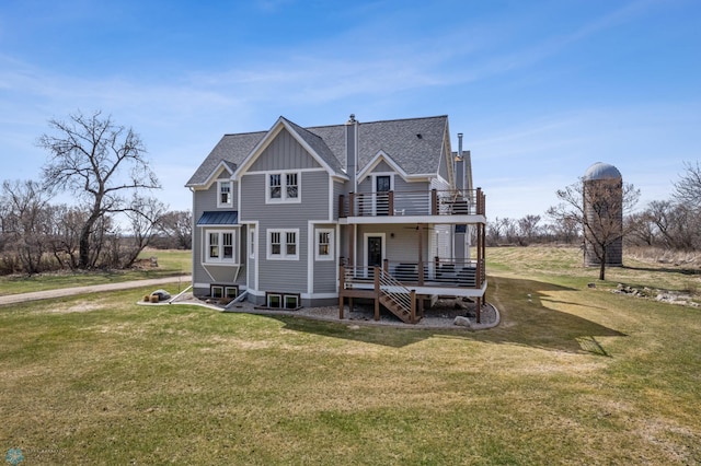 back of house with board and batten siding, a yard, a shingled roof, and a balcony