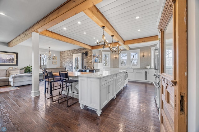 kitchen with open floor plan, white cabinets, a notable chandelier, and beamed ceiling