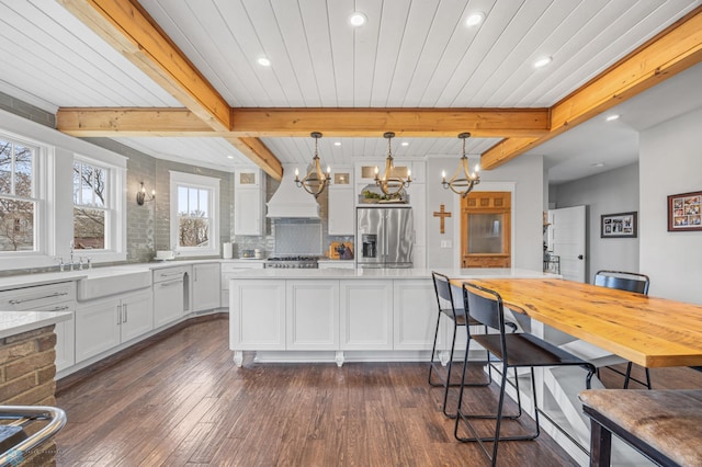 kitchen with a notable chandelier, appliances with stainless steel finishes, dark wood finished floors, and beam ceiling