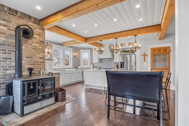 kitchen featuring dark wood finished floors, beam ceiling, white cabinets, a notable chandelier, and stainless steel appliances