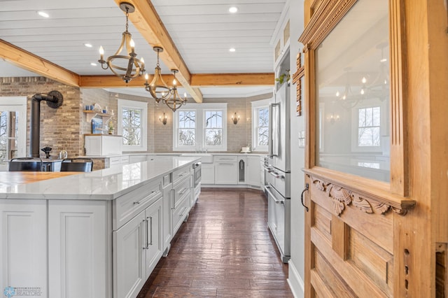 kitchen with beam ceiling, recessed lighting, white cabinets, light stone counters, and a notable chandelier