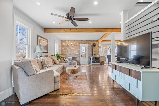 living area featuring brick wall, a wood stove, beamed ceiling, recessed lighting, and dark wood-type flooring