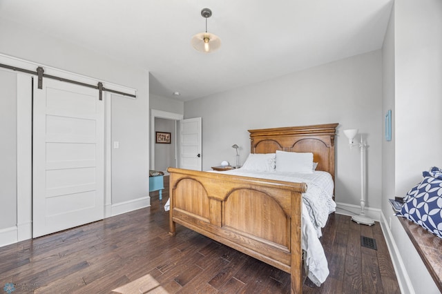 bedroom with baseboards, a barn door, and dark wood-style flooring