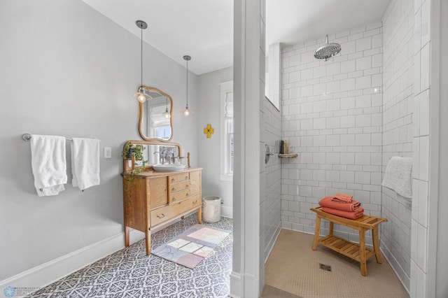 bathroom with baseboards, vanity, tile patterned floors, and tiled shower