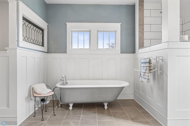 bathroom with wainscoting, a soaking tub, and a decorative wall