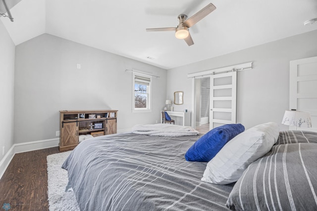 bedroom featuring wood finished floors, lofted ceiling, baseboards, a barn door, and a ceiling fan