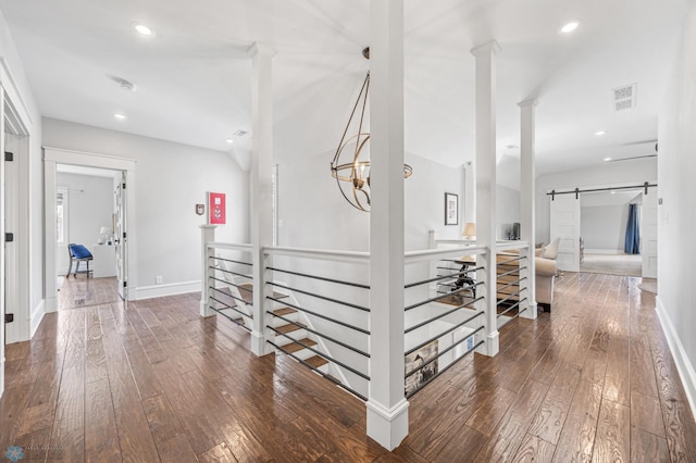 hall with wood-type flooring, recessed lighting, a barn door, and an upstairs landing