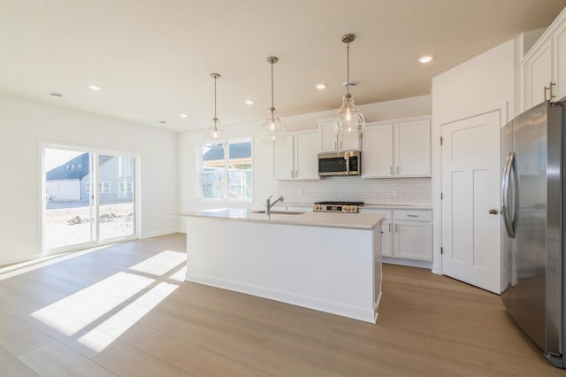 15149 Quince St NW, Andover, MN 55304 - kitchen with tasteful backsplash, a sink, white cabinets, light wood-style floors, and stainless steel appliances
