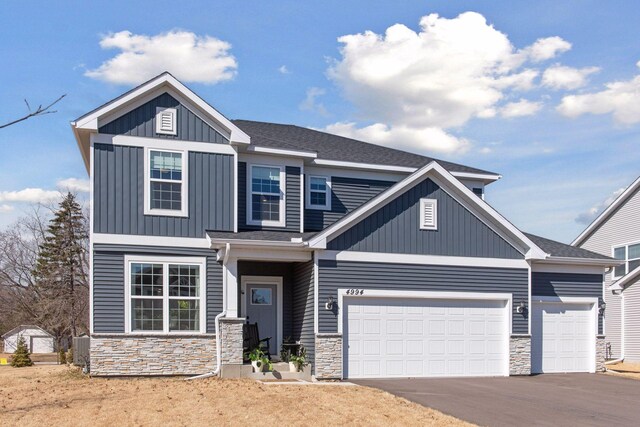 craftsman-style house with a garage, board and batten siding, driveway, and stone siding