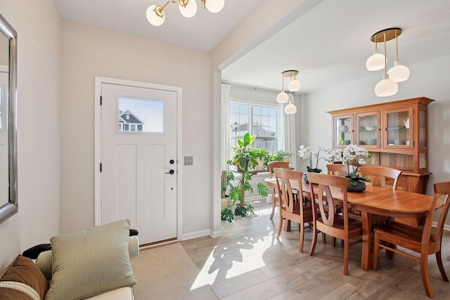 dining area with an inviting chandelier, baseboards, and light wood-type flooring