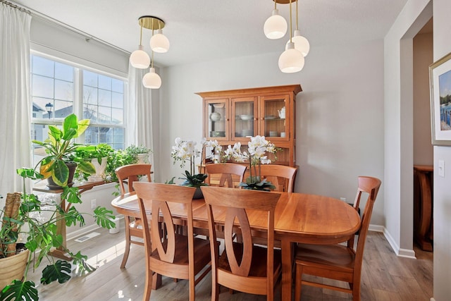 dining area with visible vents, light wood finished floors, and baseboards