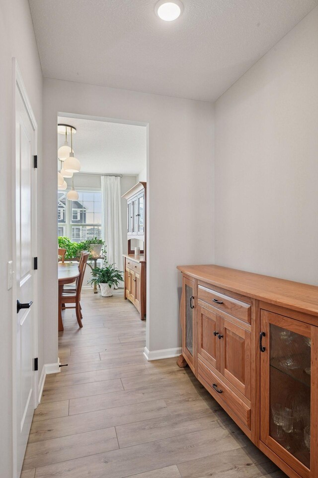 corridor featuring baseboards and light wood-style flooring