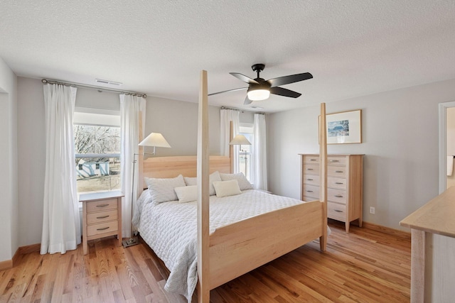 bedroom featuring light wood-style floors, ceiling fan, a textured ceiling, and visible vents