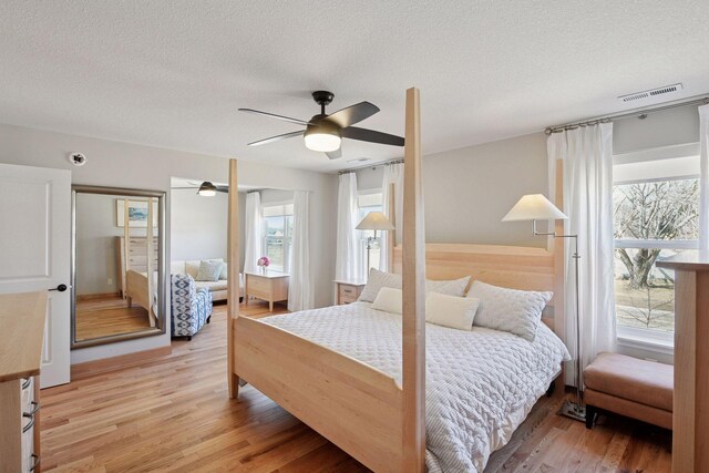 bedroom with visible vents, a ceiling fan, a textured ceiling, and light wood-type flooring