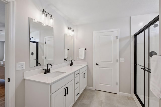 bathroom with double vanity, a sink, baseboards, and a shower stall