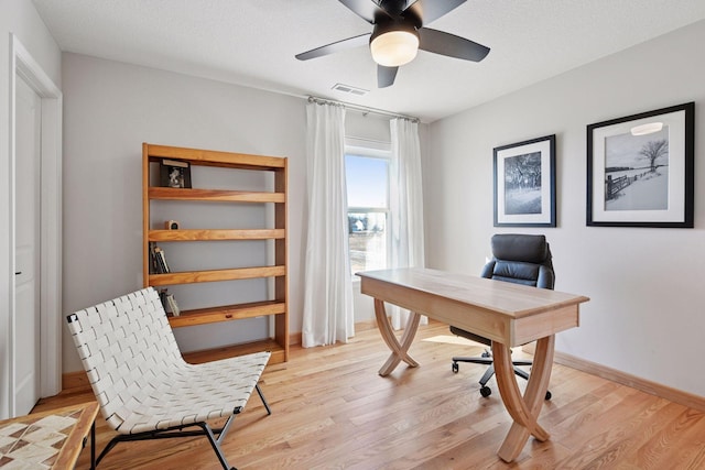 office space featuring a ceiling fan, baseboards, visible vents, and light wood-type flooring