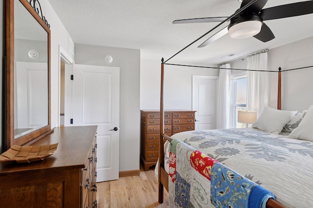 bedroom with ceiling fan, light wood-type flooring, and a textured ceiling