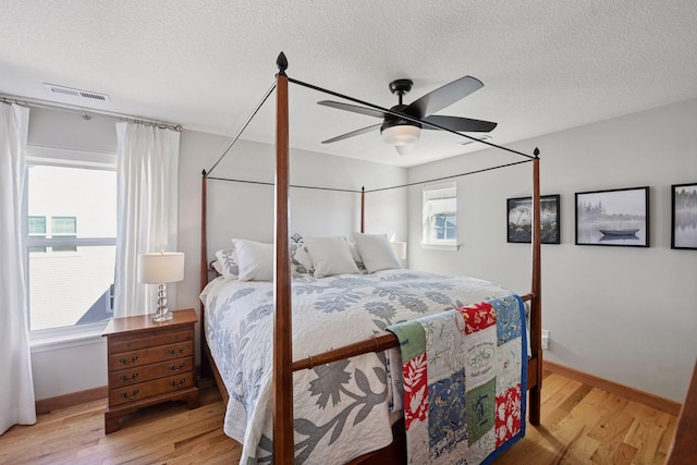 bedroom with visible vents, a textured ceiling, and light wood-style floors