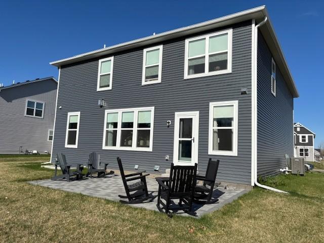 back of property featuring a lawn, central air condition unit, and a patio