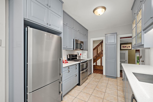 2511 12th Ave N, Minneapolis, MN 55411 - kitchen with stainless steel appliances, gray cabinets, light countertops, glass insert cabinets, and backsplash