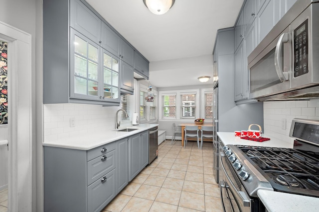 2511 12th Ave N, Minneapolis, MN 55411 - kitchen featuring appliances with stainless steel finishes, gray cabinetry, a sink, light countertops, and glass insert cabinets