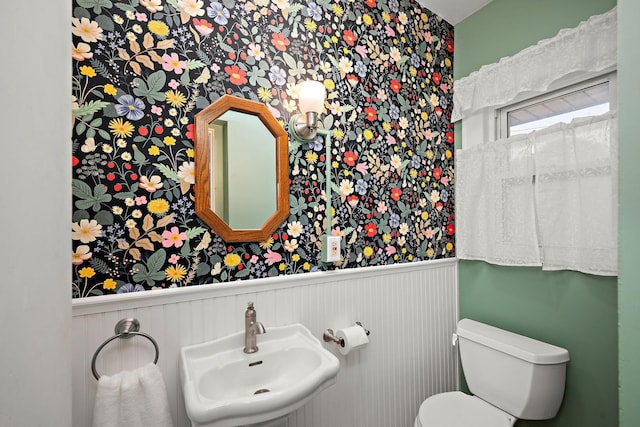 2511 12th Ave N, Minneapolis, MN 55411 - half bathroom featuring a sink, wallpapered walls, a wainscoted wall, and toilet