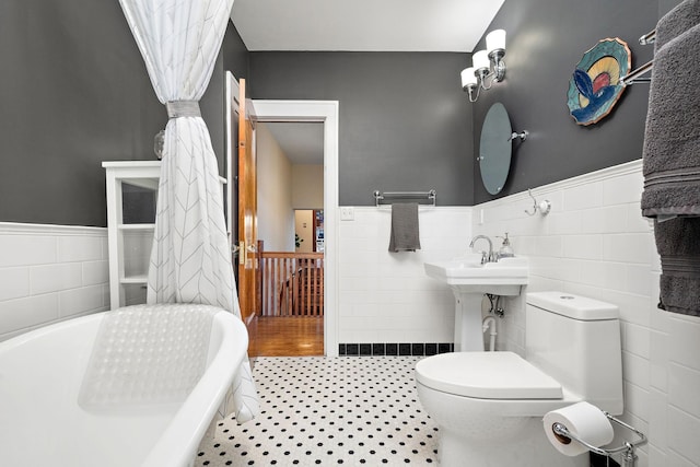 2511 12th Ave N, Minneapolis, MN 55411 - bathroom featuring tile walls, wainscoting, toilet, and a tub to relax in