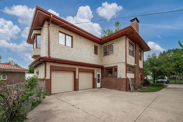 2511 12th Ave N, Minneapolis, MN 55411 - view of front of house featuring a garage, a chimney, driveway, and stucco siding