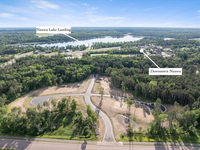 aerial view of property and surrounding area with a large body of water and a heavily wooded area