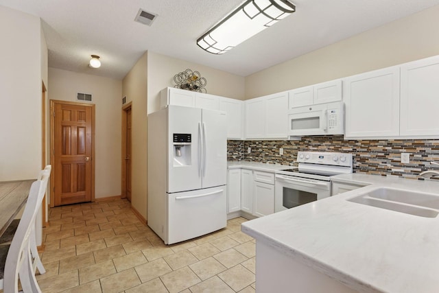 kitchen with white appliances, tasteful backsplash, visible vents, and a sink