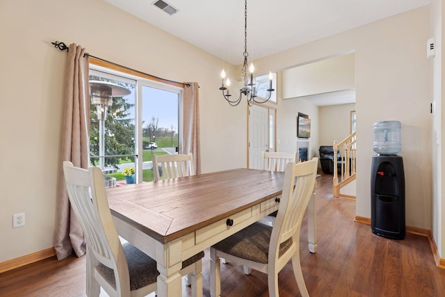 dining space with an inviting chandelier, wood finished floors, visible vents, baseboards, and stairway
