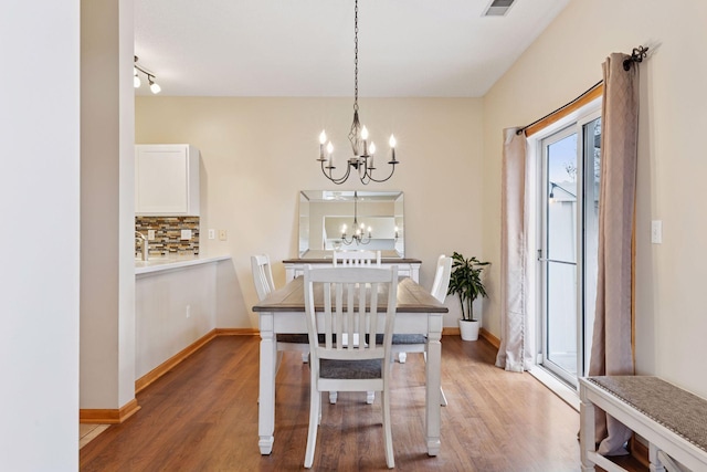 dining room featuring a chandelier, baseboards, and wood finished floors
