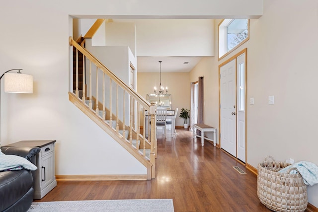 foyer featuring stairs, wood finished floors, visible vents, an inviting chandelier, and baseboards