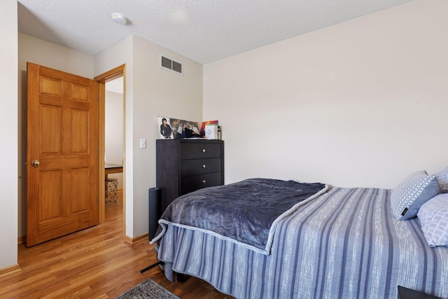 bedroom featuring a textured ceiling, light wood-type flooring, and visible vents