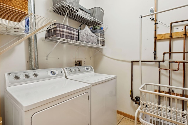 laundry room featuring washing machine and clothes dryer, baseboards, laundry area, and light tile patterned flooring
