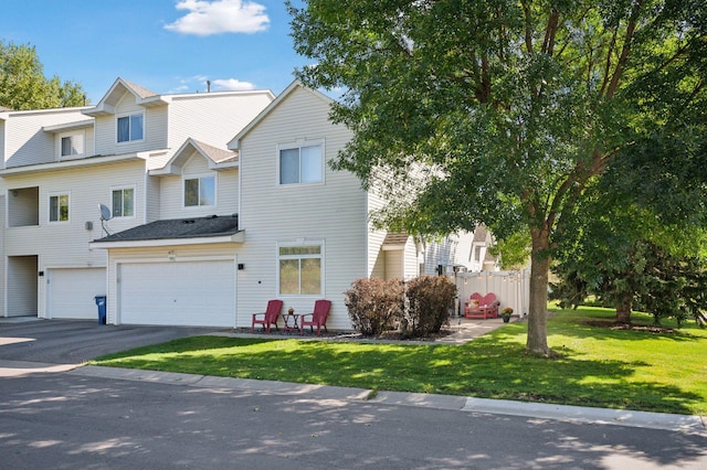 townhome / multi-family property with a front lawn, aphalt driveway, and an attached garage
